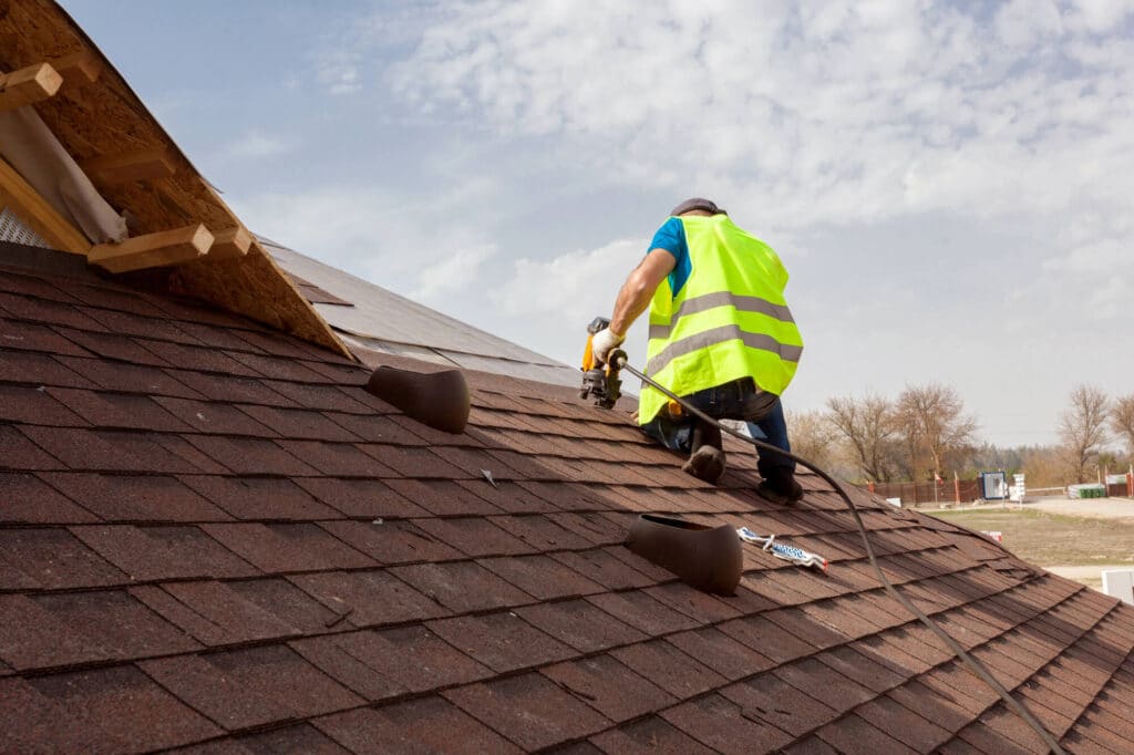 Worker installing a shingle roof